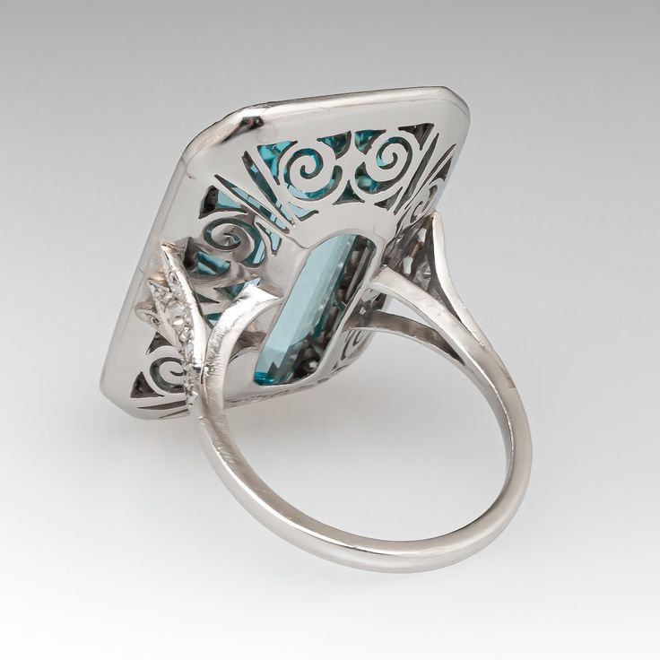 This mazing vintage cocktail ring is centered with one (1), bezel set, emerald cut natural aquamarine that is bordered with thirty-six (36), bead set, round single cut diamonds. The shoulders of the ring are each accented with three (3), bead set, round single cut diamonds. The gemstones are bordered with milgrain edging. The ring measures 28.9mm X 18.7mm at the top, rises 9.1mm above the finger, tapering to 1.7mm wide and 1.3mm thick at the base of the shank. It is currently a size 7. Elegant Multi-stone Rectangular Rings, Elegant Rectangular Multi-stone Rings, Elegant Octagon Multi-stone Ring, Formal Multi-stone Octagon Rings, Formal Rectangular Emerald Ring With Polished Finish, Platinum Octagon Ring With Gemstone, Formal White Gold Topaz Ring With Rectangular Stone, Rectangular Platinum Ring For Formal Occasions, Formal Octagon Multi-stone Rings