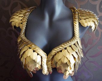 a mannequin with gold leaves on it's chest and hands in the shape of wings