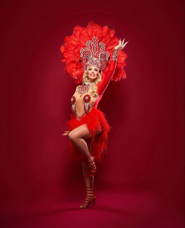 a woman in a red costume is posing for a photo with her arms up and legs spread out