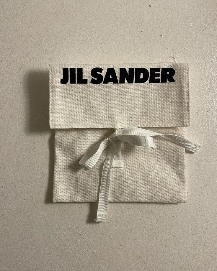 a piece of cloth with the word jil sander on it and a white ribbon tied around it