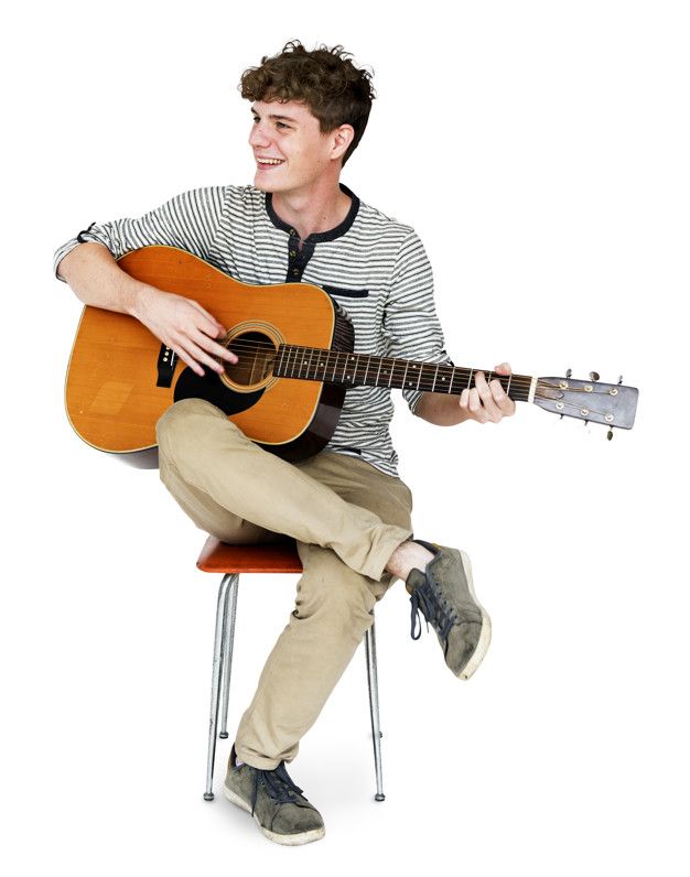 a young man sitting on a chair holding an acoustic guitar and smiling at the camera