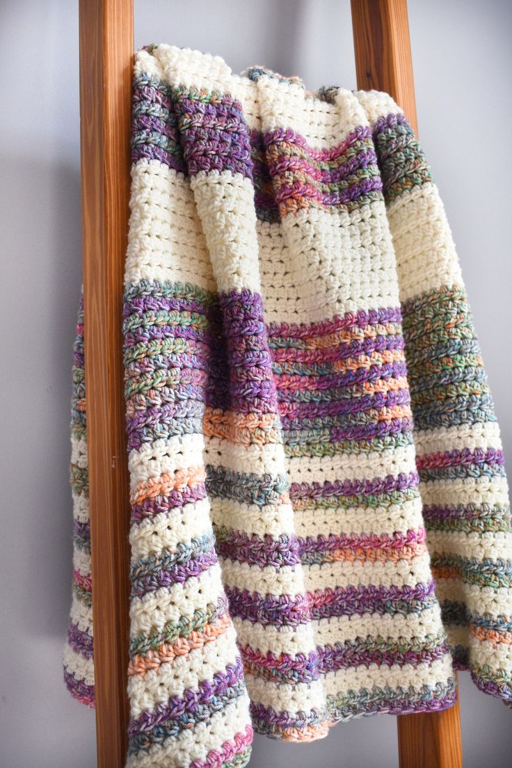 a crocheted blanket hanging on a wooden ladder