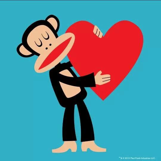 a monkey holding a big heart with his face to the side on a blue background