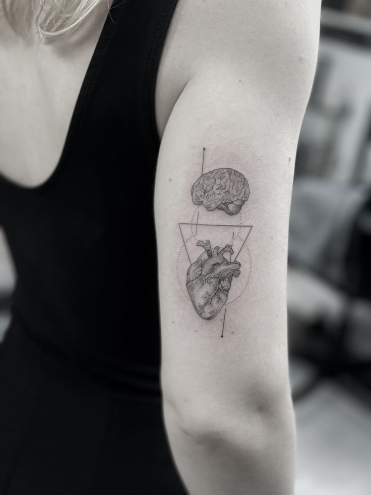 a woman with a tattoo on her arm that has two halves in the shape of heart and brain