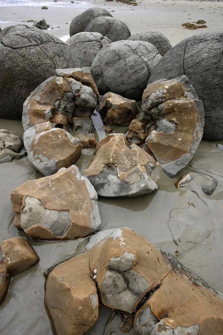 several large rocks sitting on top of a sandy beach