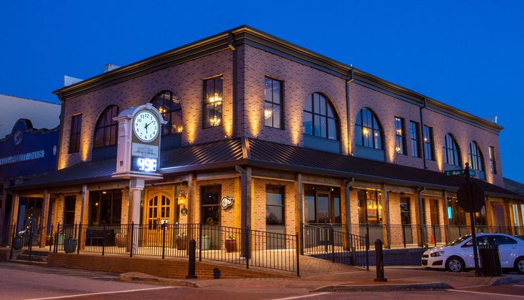 an old brick building with a clock on it's front and side windows at night