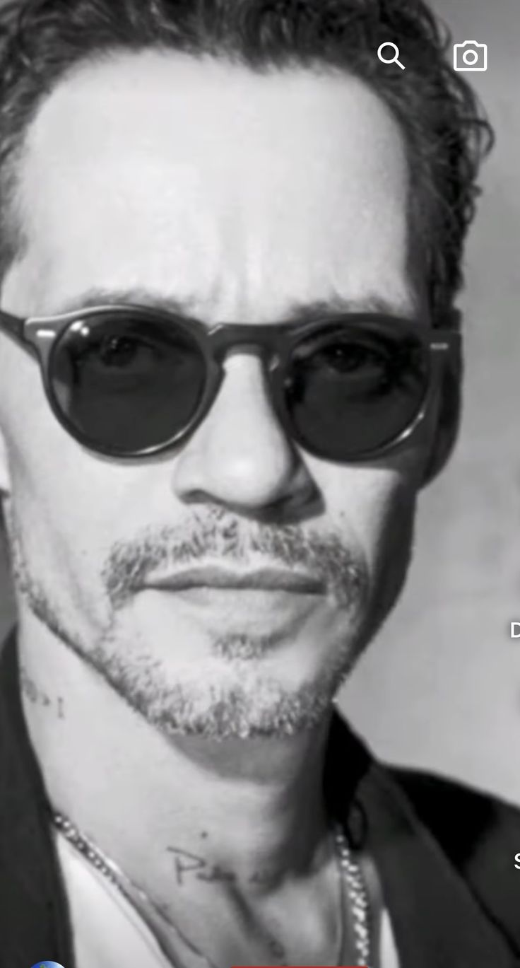 a man wearing sunglasses and looking at the camera with an ad in front of him