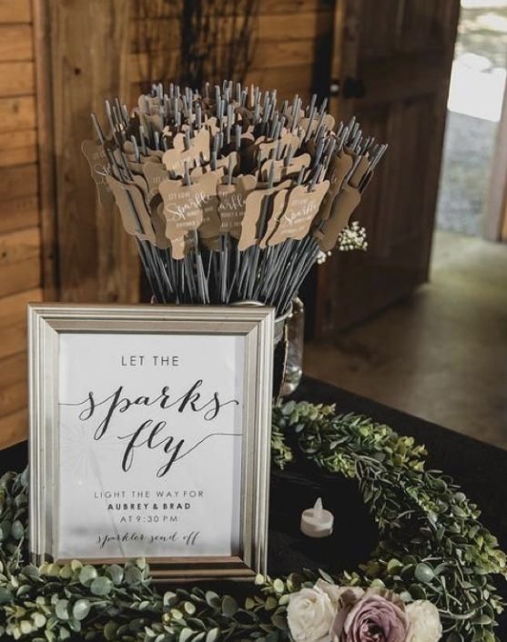 a table topped with flowers and a sign that says let the sparkles fly on it