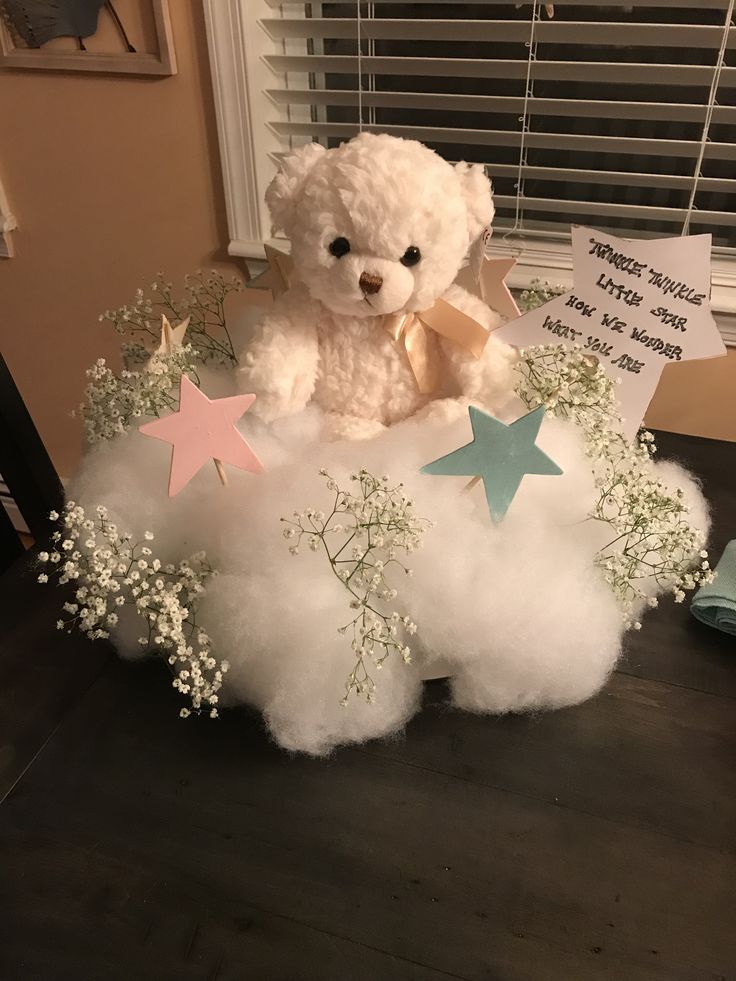 a teddy bear sitting on top of a cloud filled with baby's breath flowers