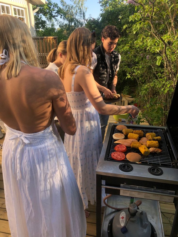 some people are grilling donuts on a bbq with two women in white dresses