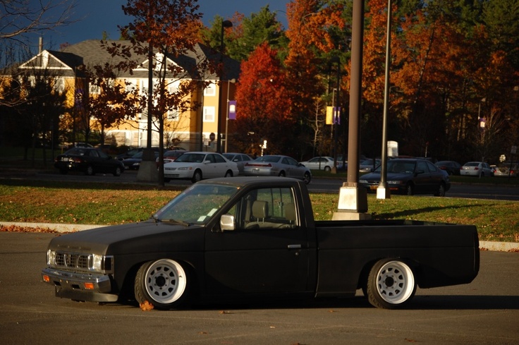 a black truck parked in a parking lot next to a street light and some houses