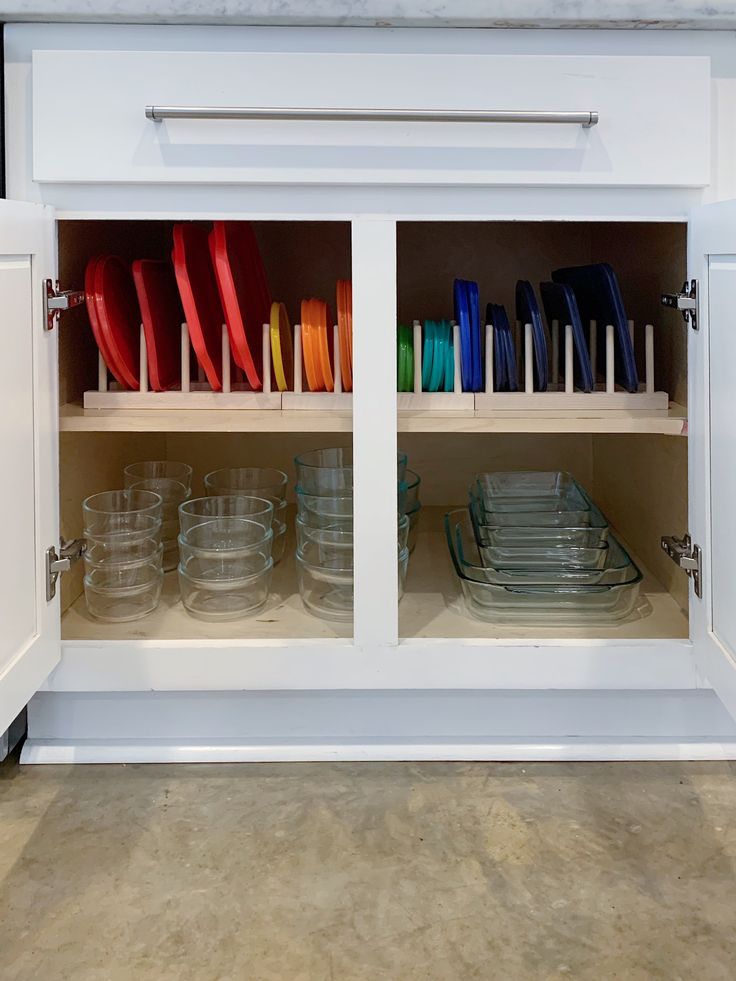 an open cabinet with plates and bowls in the bottom section, on top of white cabinets