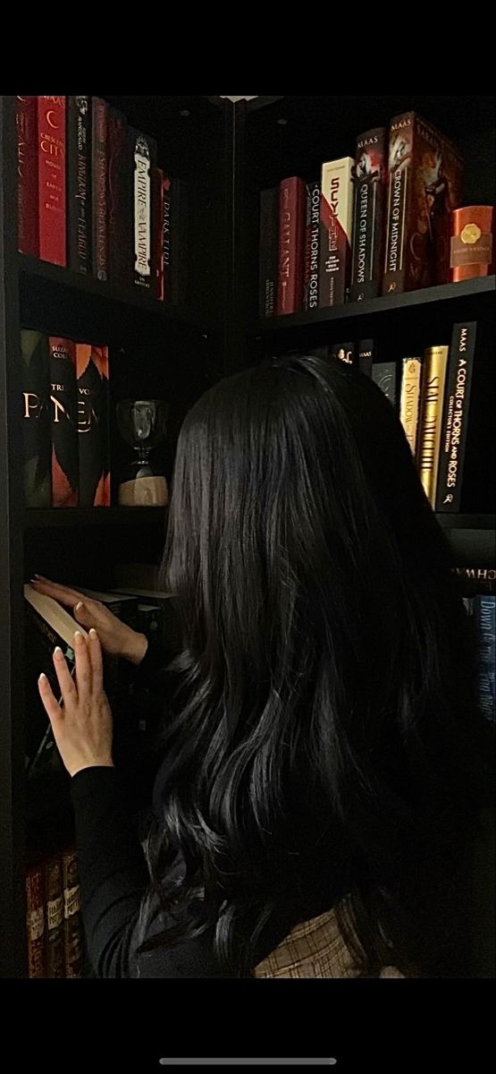 a woman standing in front of a bookshelf with her hand on the book