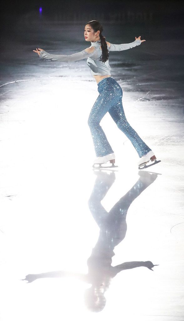 a female figure skating on an ice rink with her arms spread out in the air