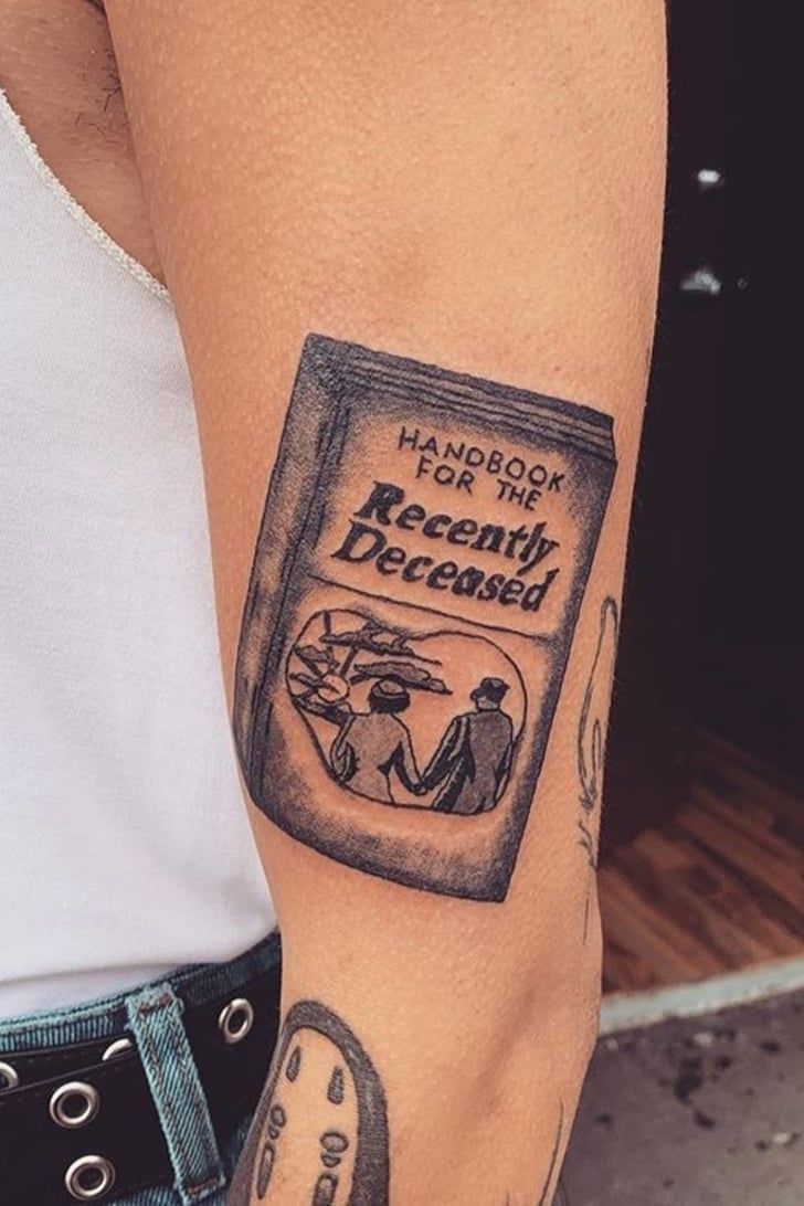 a woman with a tattoo on her arm holding onto a book that reads harry potter