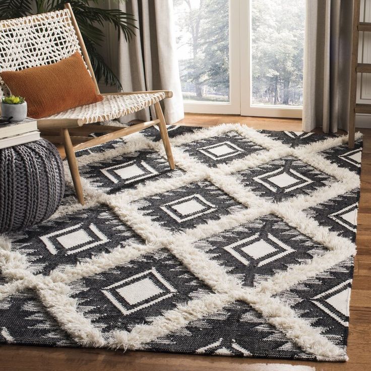 a black and white rug in a living room next to a chair with a plant on it