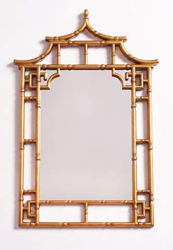 a mirror that is sitting on top of a white wall with gold trimmings