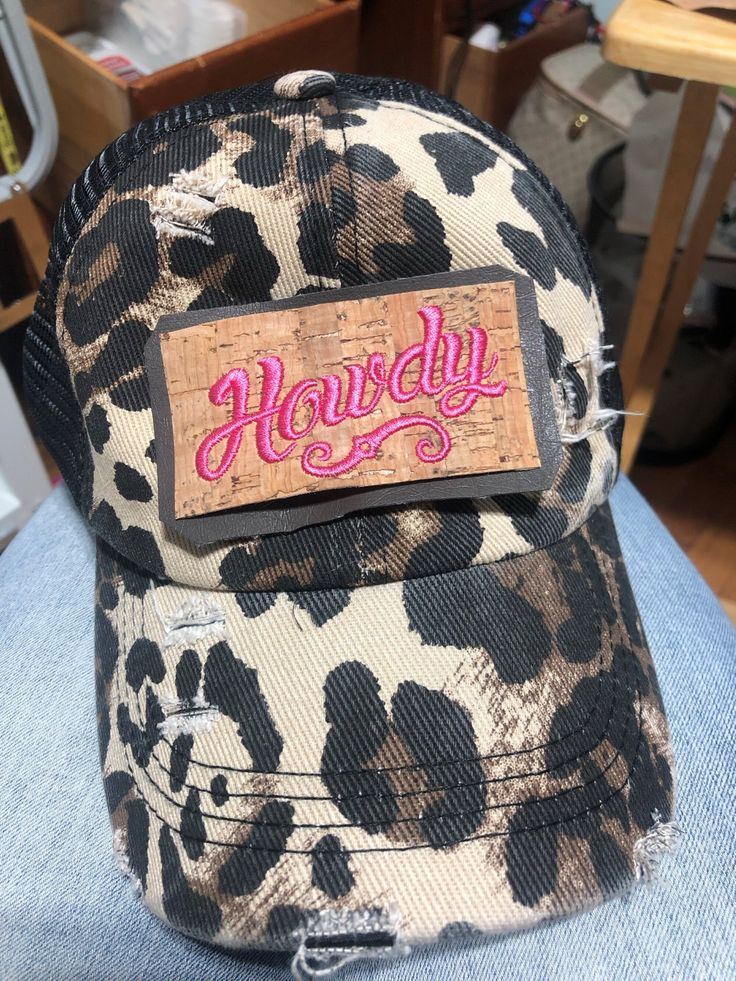 "Time to Cowgirl Up and let them know you're ready to play! Leopard print distressed trucker hat. Elastic criss-cross, ponytail back.  \"Howdy\" embroidered on faux leather  (Distressing may vary on cap and patch due to manufacturing processes)" Trendy Distressed Adjustable Trucker Hat, Trendy Distressed Snapback Trucker Hat, Trendy Adjustable Distressed Trucker Hat, Trendy Distressed Trucker Hat, Cowgirl Up, Adjustable Distressed Brown Trucker Hat, Distressed Brown Baseball Cap One Size, Patched Trucker Hat, Distressed Brown Trucker Baseball Cap