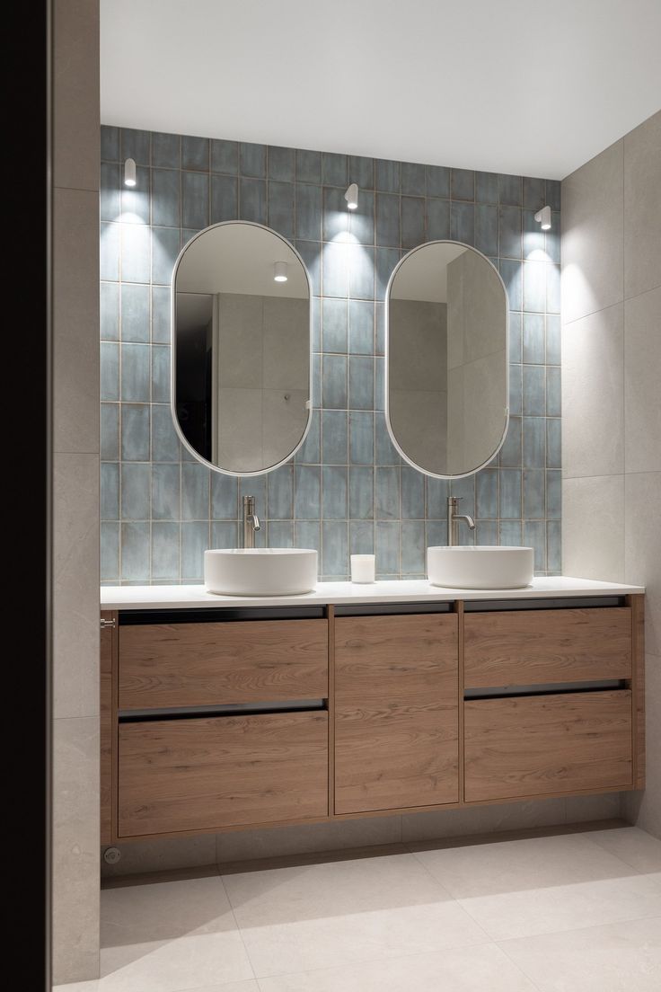 a bathroom with two sinks and three mirrors on the wall next to eachother