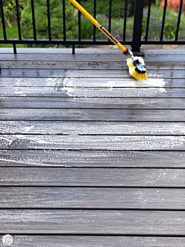 a person using a broom to clean a deck