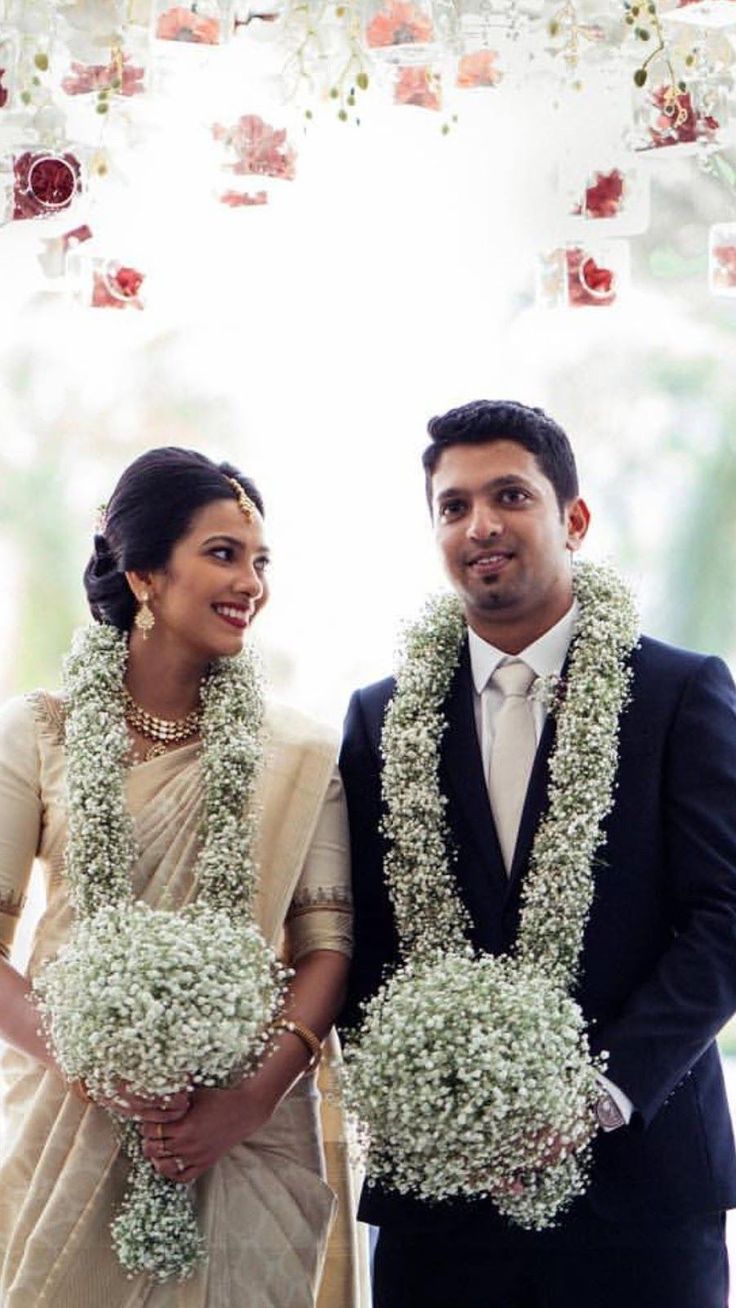 a man and woman standing next to each other in front of a flower covered archway