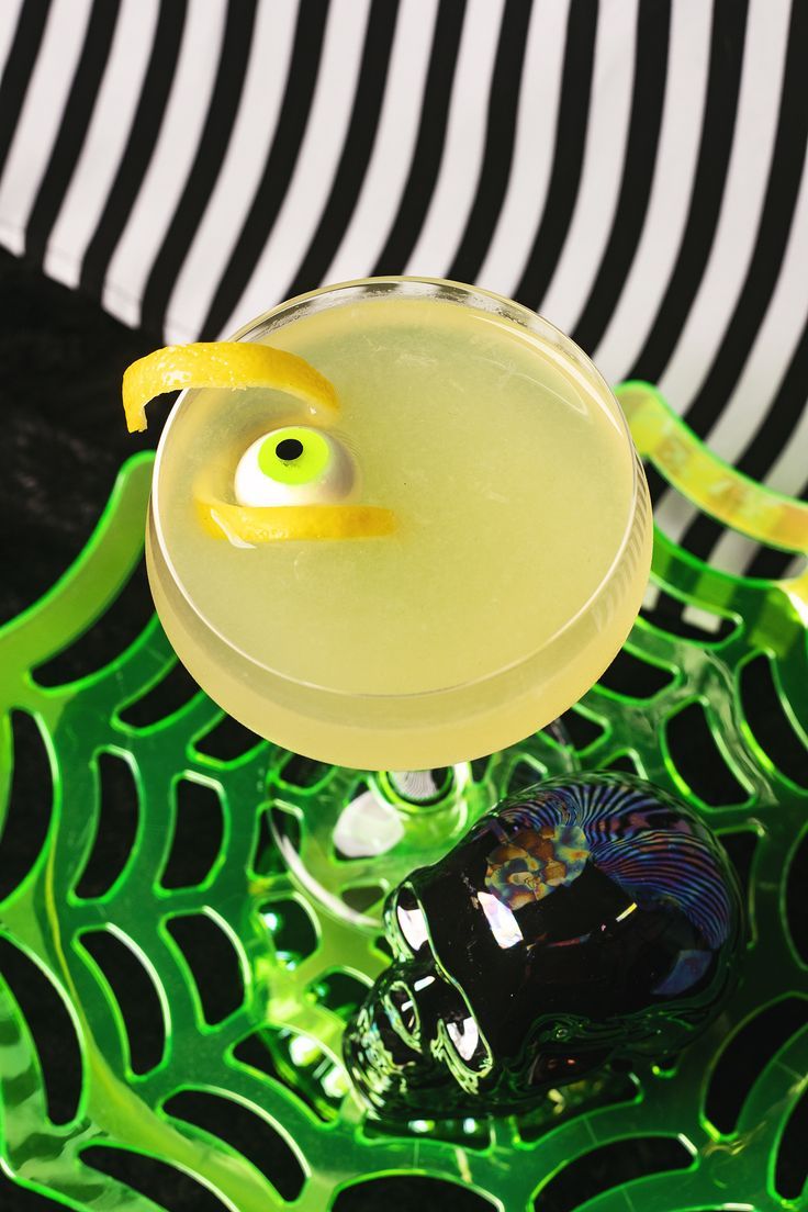 a yellow drink sitting on top of a green table next to a black and white striped wall