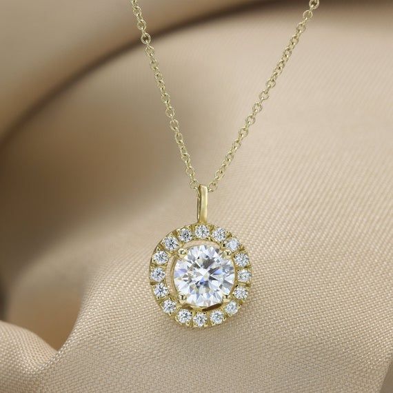 Luxurious and Elegant Moissanite necklace handmade in solid gold.Beautifully crafted this exquisite pendant hangs from a matching gold link chain perfect for everyday.You will love the unmatched sparkle from the 1 Carat Moissanite at its center and surrounded by a halo of smaller Moissanites gemstones that are full of fire and diamond sparkle.Fit for a princess or Queen this necklace has all the beauty and sparkle you ever wanted in one superbly made piece.Handmade by an inspired jewelry artist Dazzling Gold Moissanite Necklaces, Timeless Gold Jewelry With Halo Setting, Gold Diamond Halo Necklace For Gift, Round Halo Design Necklace For Gift, Gold Diamond Pendant Necklace With Halo, Oval Pendant Halo Jewelry For Gift, Halo Oval Pendant Jewelry As Gift, Dazzling Solitaire Necklace With Halo Design For Gift, Moissanite Pendant Necklace In Yellow Gold