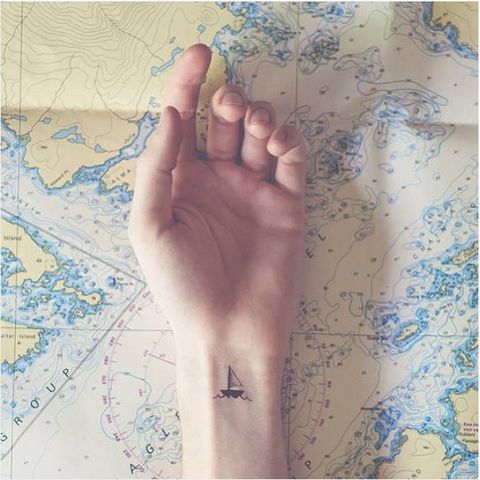 a person's arm with a small airplane tattoo on it, sitting next to a map