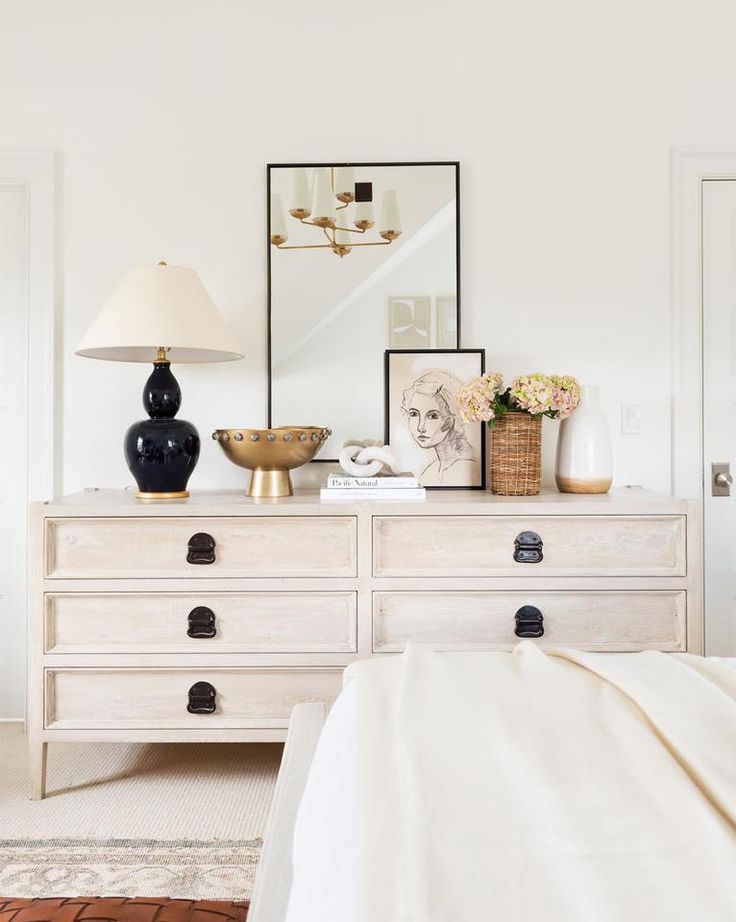 a white dresser with two lamps on top of it and pictures above the drawers in front of them