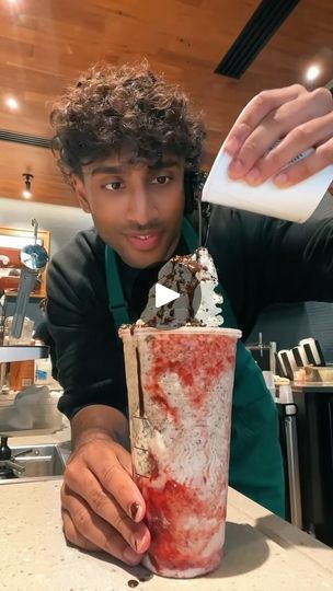 a man is pouring something into a cup with ice cream on top and sprinkles in it