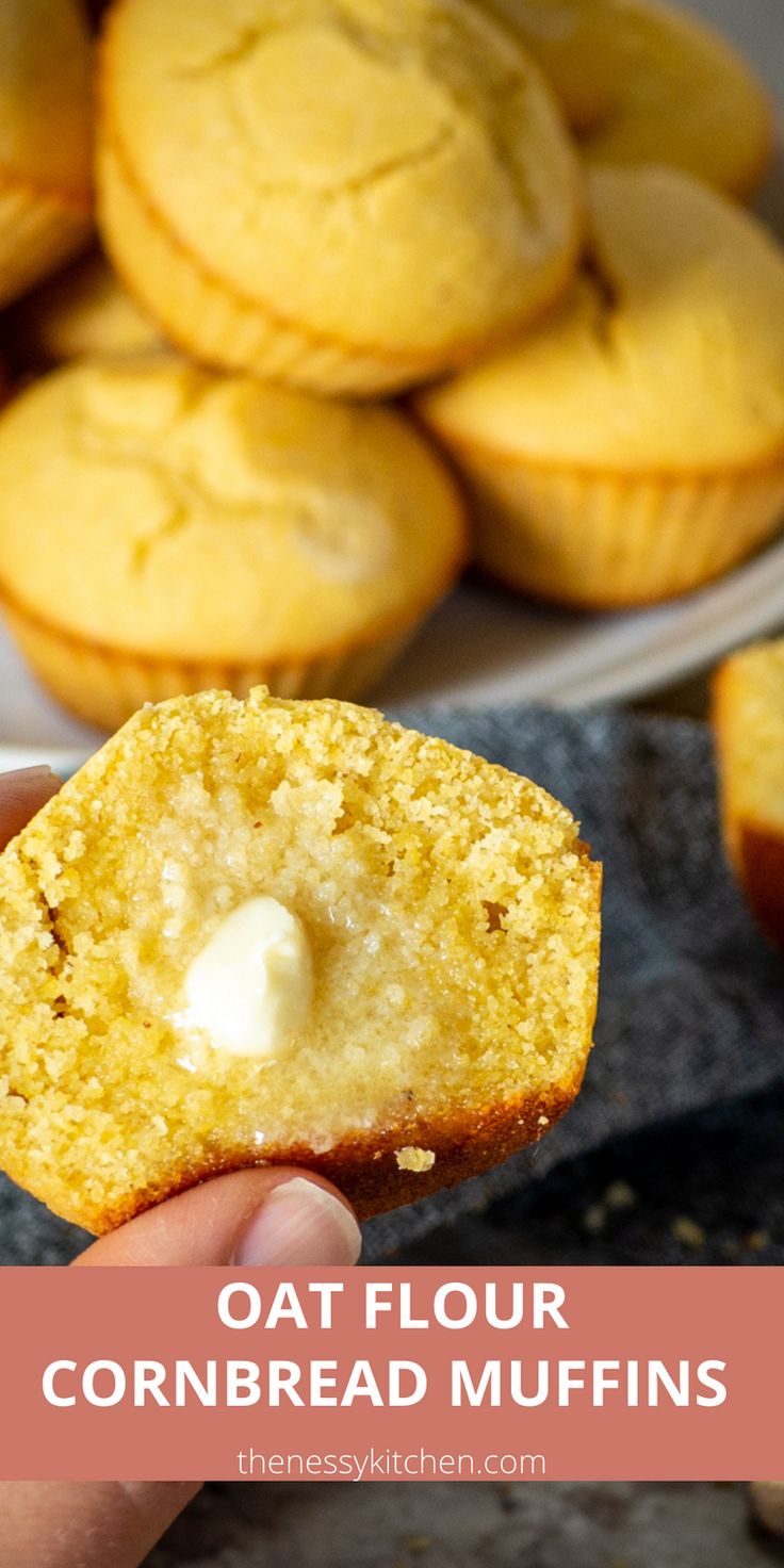 a hand holding a cornbread muffin in front of some other muffins