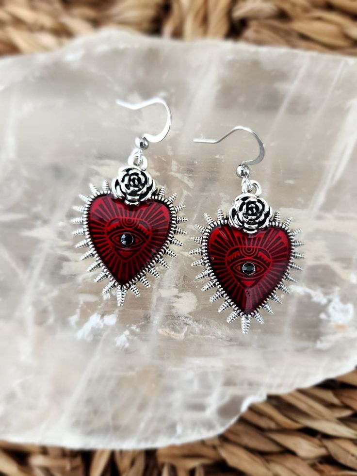 a pair of red heart shaped earrings sitting on top of a basket