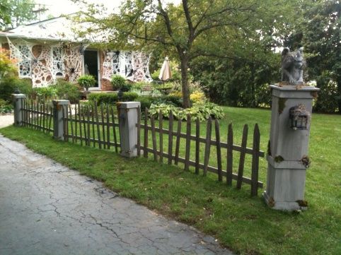 a wooden fence in front of a house with a dog statue on the top of it