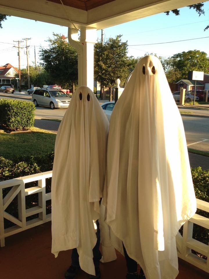 two white ghost statues sitting on top of a porch