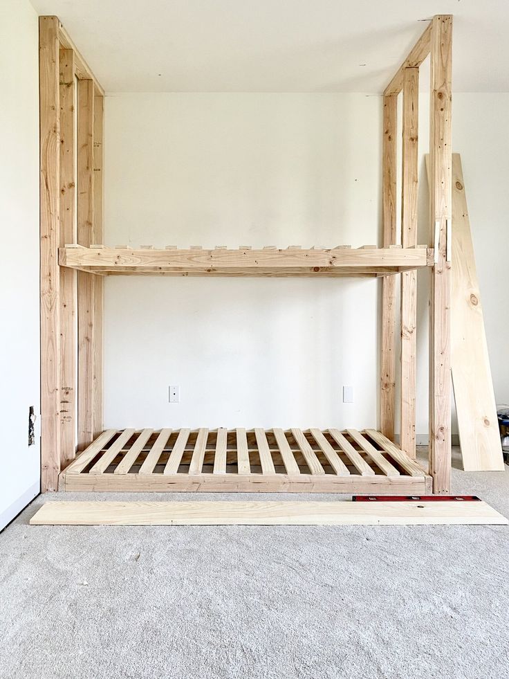 a wooden bed frame sitting in the middle of a room with carpet on the floor