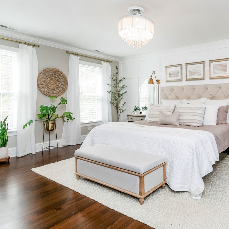 a bedroom with white walls and wood flooring has a large bed in the center