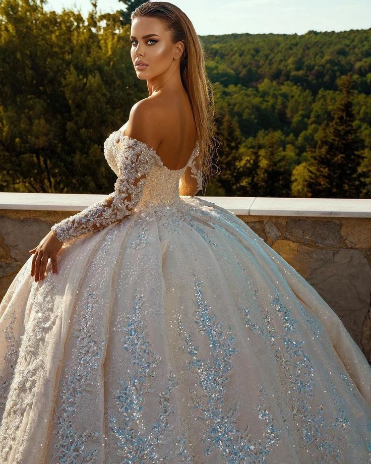 a woman in a wedding dress standing on a ledge with her back turned to the camera