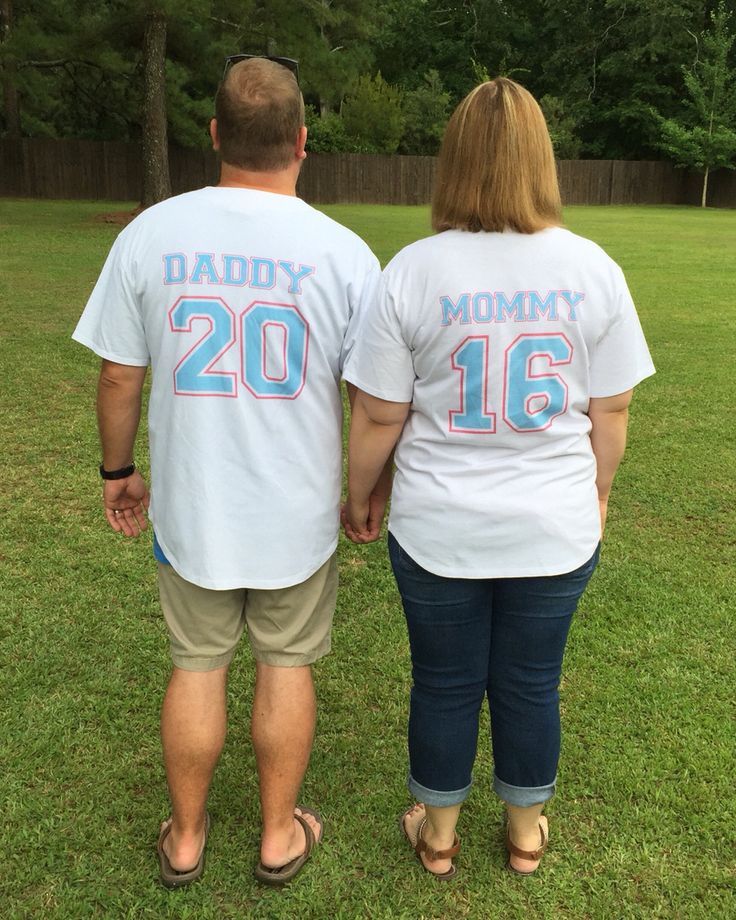 a man and woman in matching shirts holding hands while standing next to each other on the grass