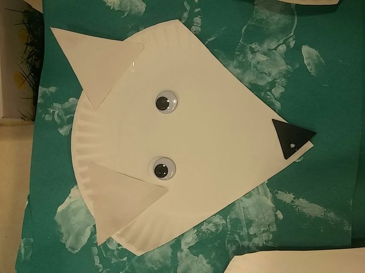 a paper plate shaped like a fish sitting on top of a green sheet of paper