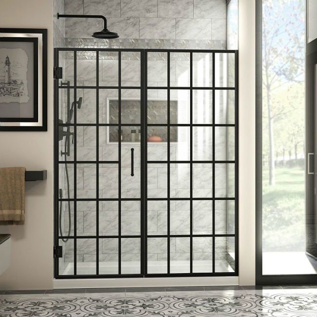 a bathroom with a glass shower door and tiled flooring, framed pictures on the wall