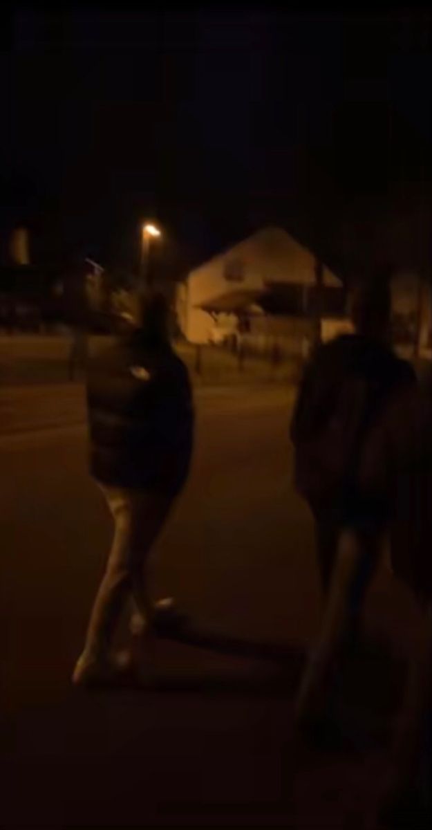 two people walking down the street at night