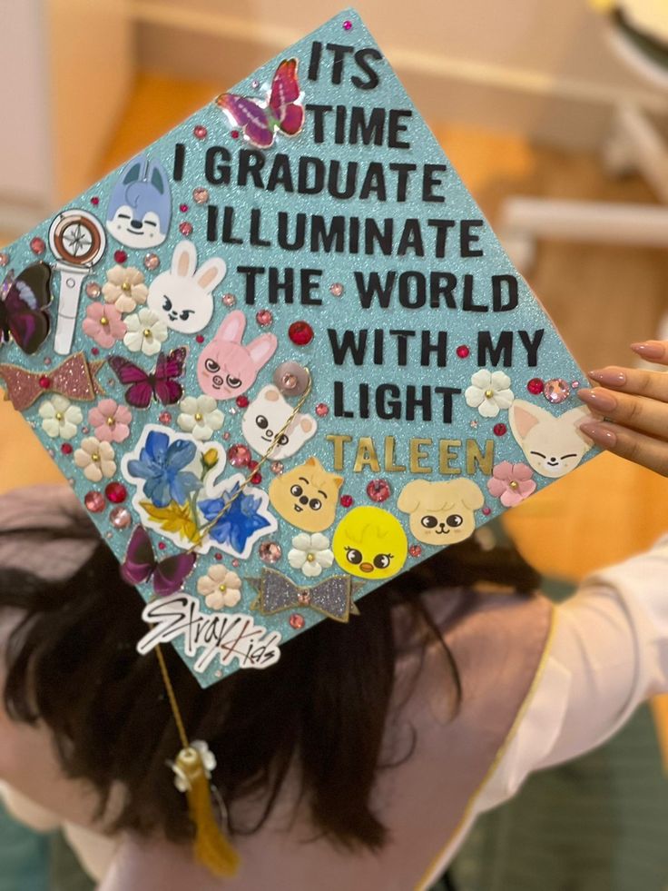 a woman wearing a blue graduation cap with stickers on it's back and writing that reads, its time i graduate illuminate the world with my light