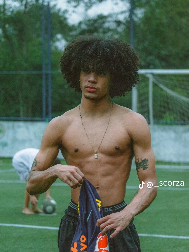 a shirtless young man holding a soccer jersey