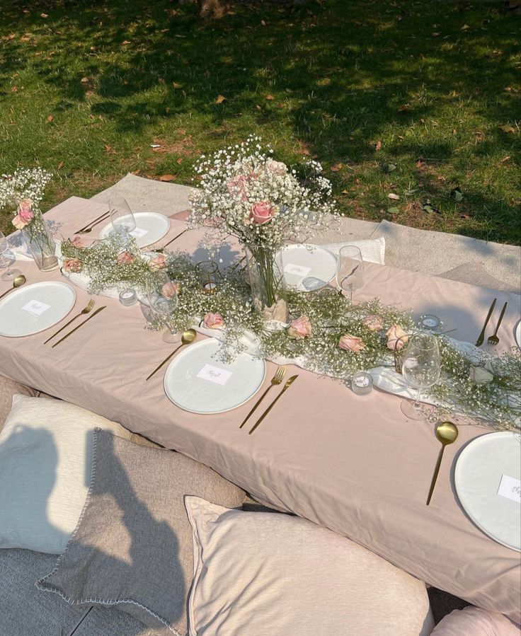 a table set up with plates and flowers on it for a wedding reception in the park