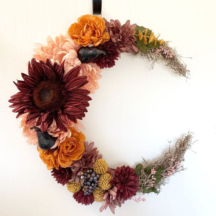 a wreath made out of dried flowers on a white background with the letter o in the middle