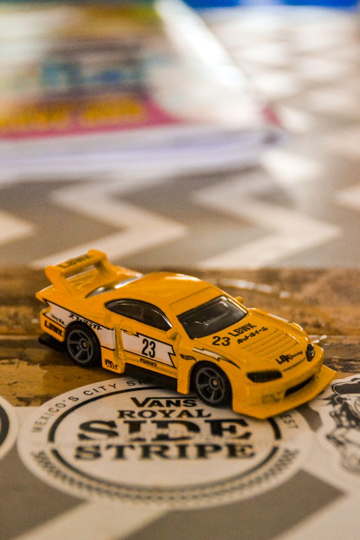 a yellow toy car sitting on top of a checkered table with stickers around it