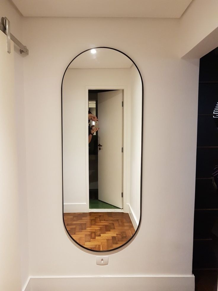 an oval mirror on the wall above a wooden floor