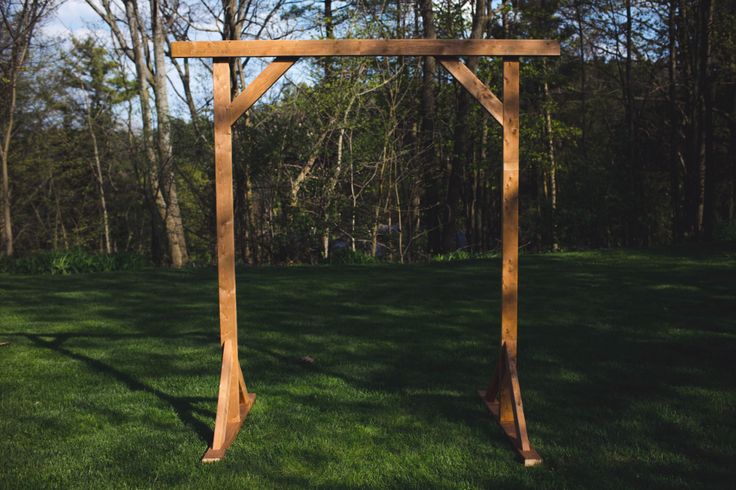 a wooden structure sitting in the middle of a lush green field