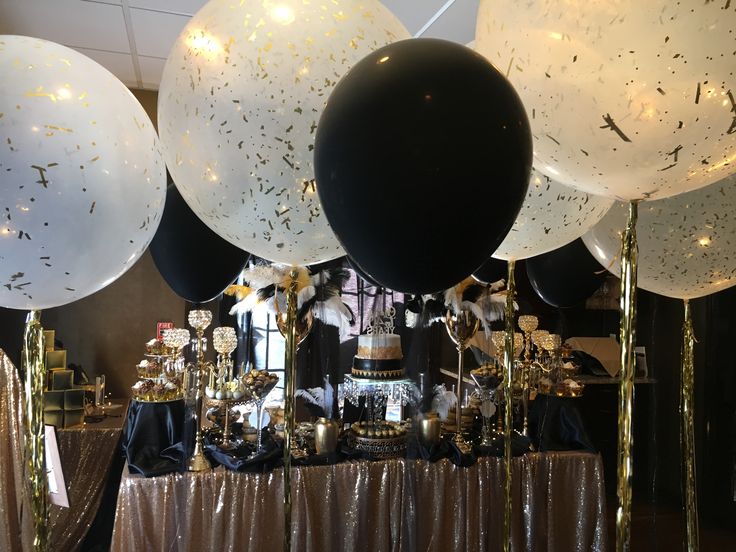 black and white balloons are hanging from the ceiling above a table with gold sequins