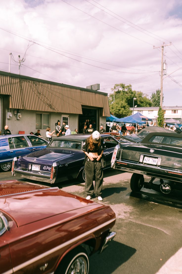 several cars parked in a parking lot with people standing around